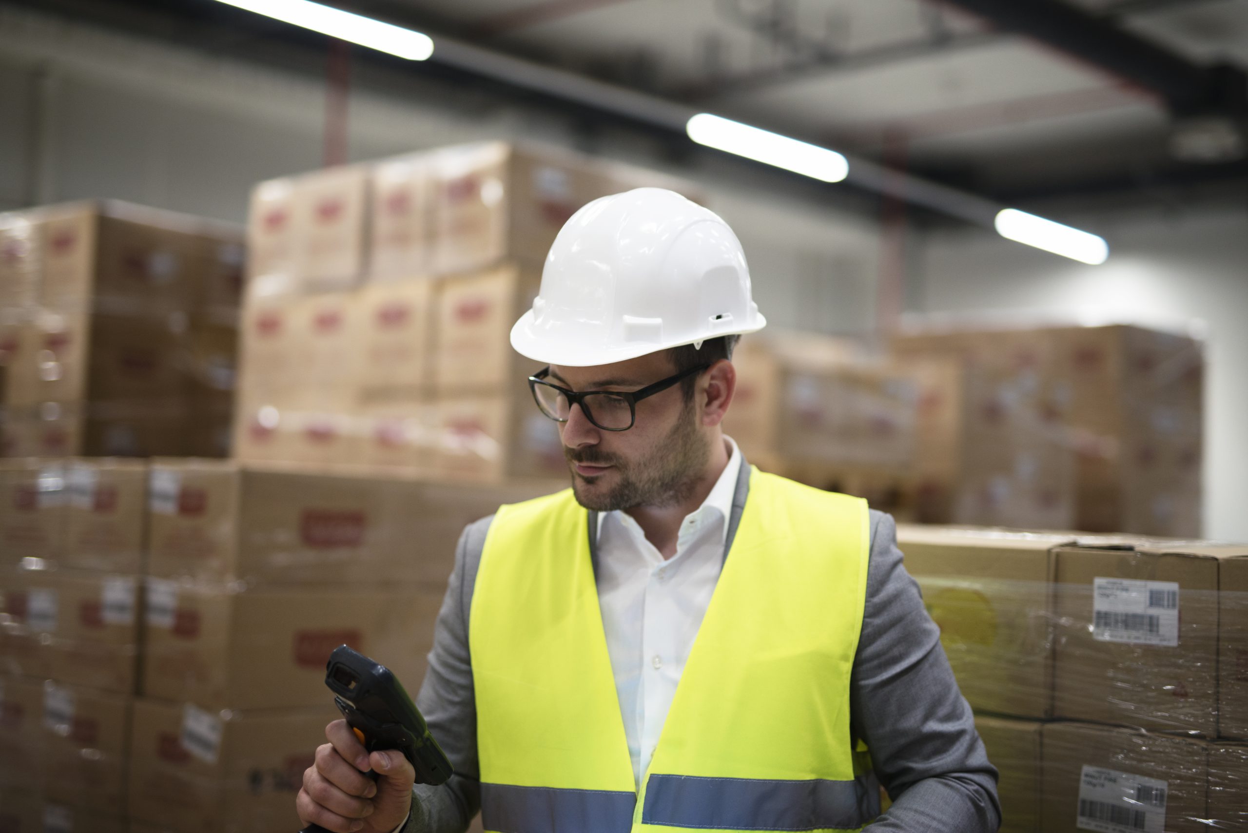 industrial worker with bar code scanner keeping track and controlling goods arriving in warehouse.